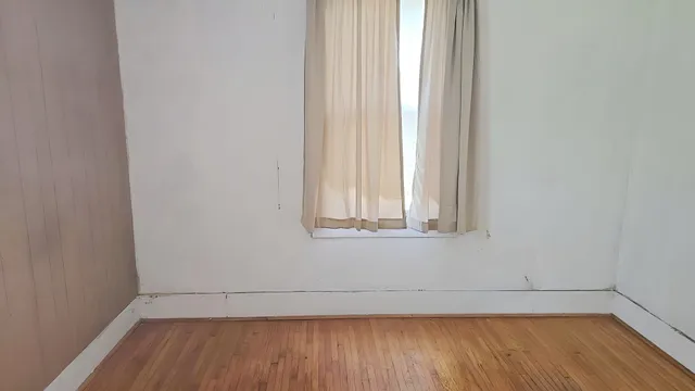 a view of a small space with wooden floor and a window