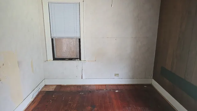 a view of a small space with wooden floor and a window