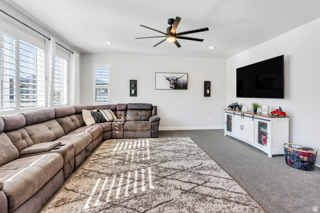 252 North Sunrise Rnch Drive Mapleton, UT 84664 - Photo 13 of 62 Spacious living area featuring light gray carpet, multiple large windows with plantation shutters, a dark-bladed ceiling fan, and recessed lighting