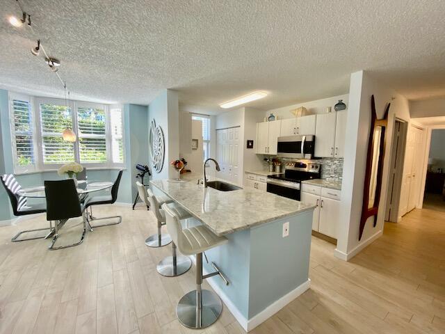3594 South Ocean Boulevard, Unit 207 Highland Beach, FL 33487 - Photo 5 of 56 a kitchen with stainless steel appliances kitchen island granite countertop a refrigerator a stove a sink a dining table and chairs with wooden floor