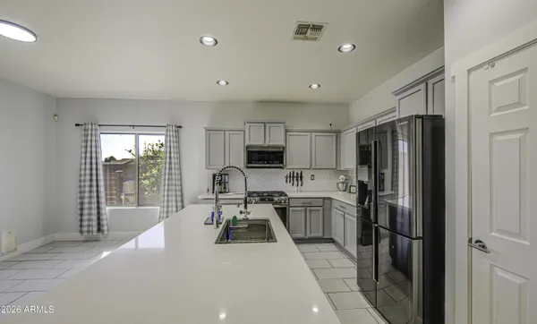 a kitchen with stainless steel appliances granite countertop a stove top oven a sink a dining table and chairs