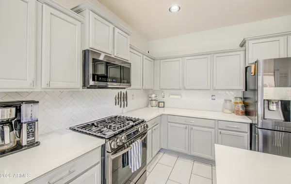 a large white kitchen with lots of appliances a stove a table and chairs