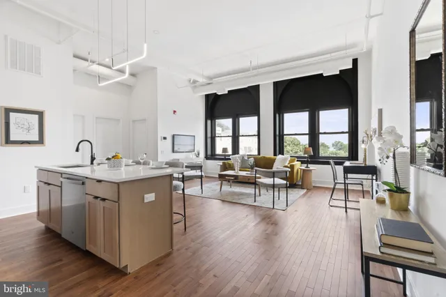 a living room with stainless steel appliances granite countertop furniture wooden floor and a large window