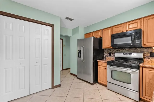 a kitchen with granite countertop a stove top oven and refrigerator