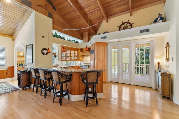 a dining hall with stainless steel appliances granite countertop a stove a refrigerator a dining table and chairs with wooden floor