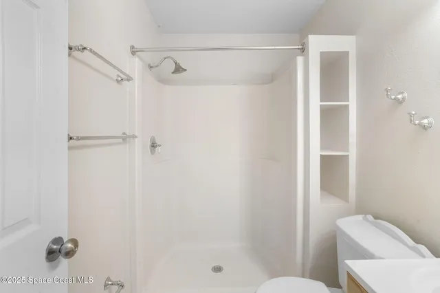 an empty room with a chandelier fan and wooden floor
