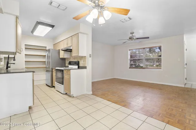 an empty room with wooden floor chandelier fan and windows