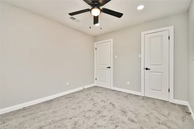 an empty room with a ceiling fan and carpet