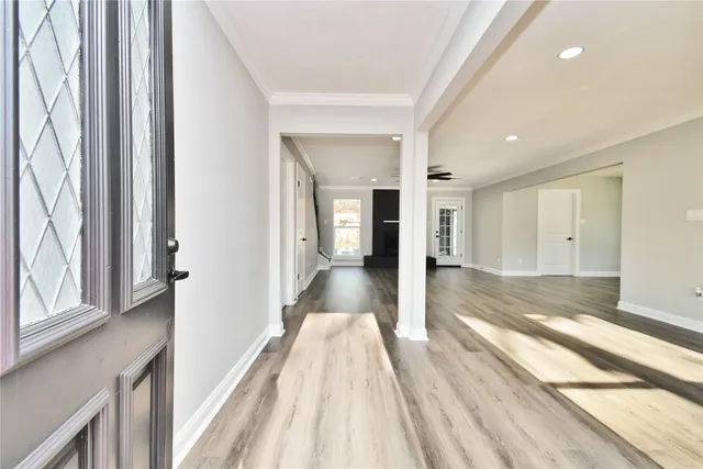 a view of a hallway with wooden floor and a bathroom