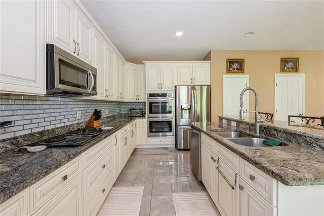 a large kitchen with granite countertop a sink stainless steel appliances and cabinets