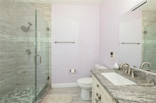 a bathroom with a granite countertop sink a toilet and shower