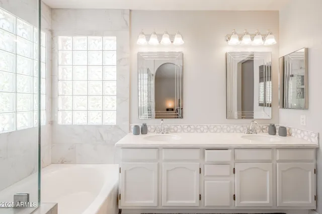 a bathroom with a double vanity sink bathtub and next to a window