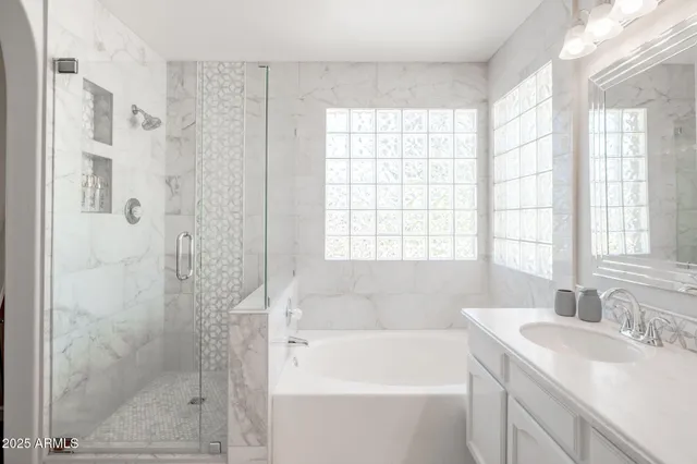 a bathroom with a granite countertop sink a large mirror and a bathtub