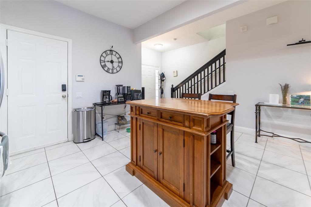 1041 Enclair Street Orlando, FL 32828 - Photo 22 of 62 a kitchen with stainless steel appliances granite countertop a stove a chimney a dining table and chairs