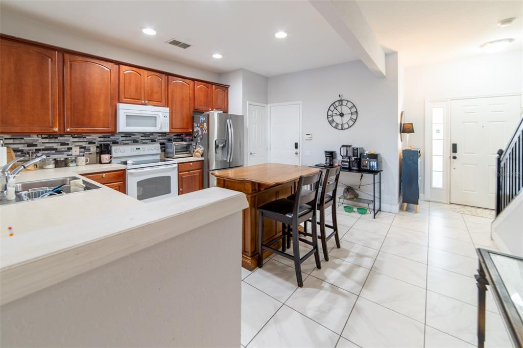 1041 Enclair Street Orlando, FL 32828 - Photo 33 of 62 a kitchen with stainless steel appliances granite countertop a stove top oven a sink a dining table and chairs with the front door