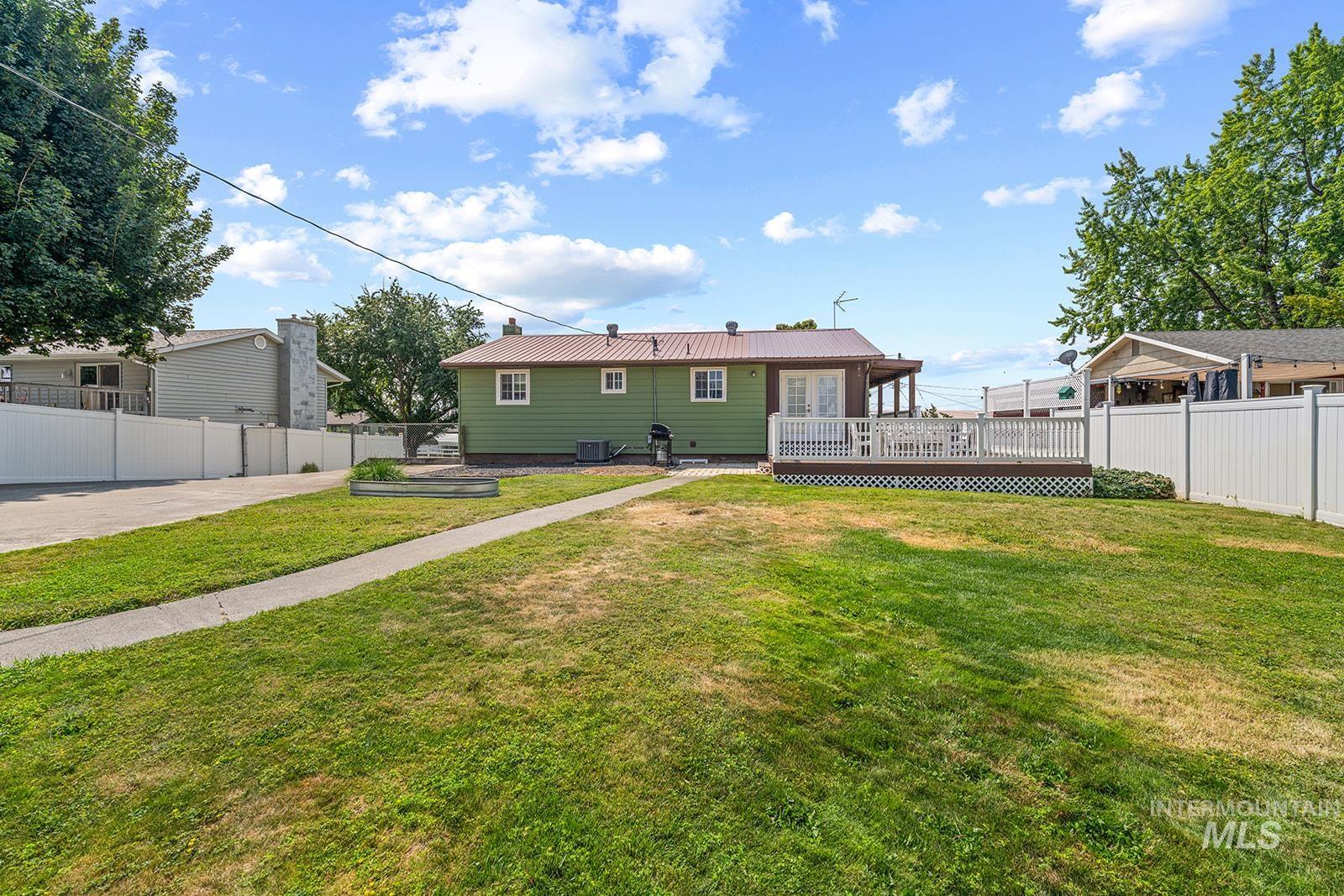 2007 Ripon Avenue Lewiston, ID 83501 - Photo 18 of 30 Expansive backyard featuring a concrete pathway, a wooden deck with white railings, a raised garden bed, and a full privacy fence