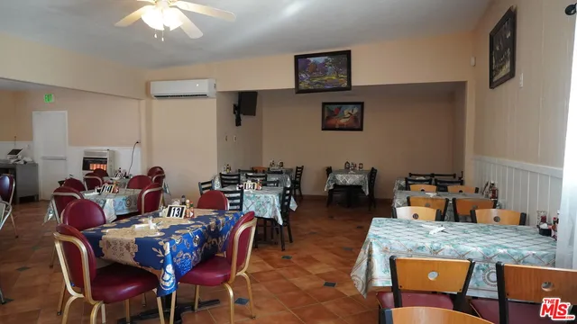 a dining room with stainless steel appliances kitchen island granite countertop a table chairs and a refrigerator