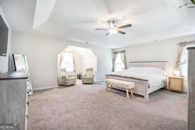 a spacious bedroom with a bed a chandelier and a large window