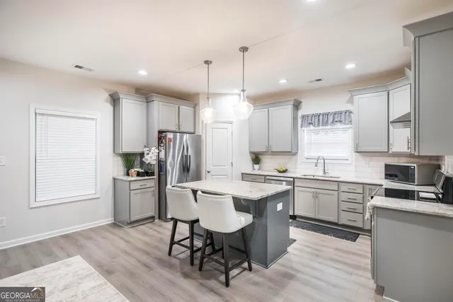 a kitchen with kitchen island granite countertop a sink cabinets and stainless steel appliances