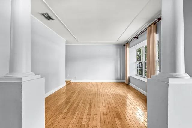 a view of empty room with wooden floor and fan