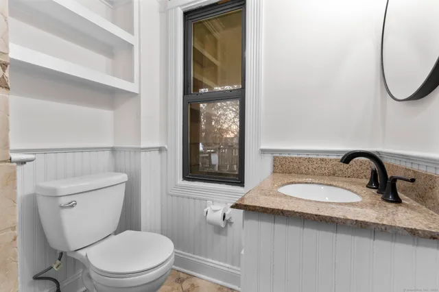 a bathroom with a granite countertop toilet sink and mirror