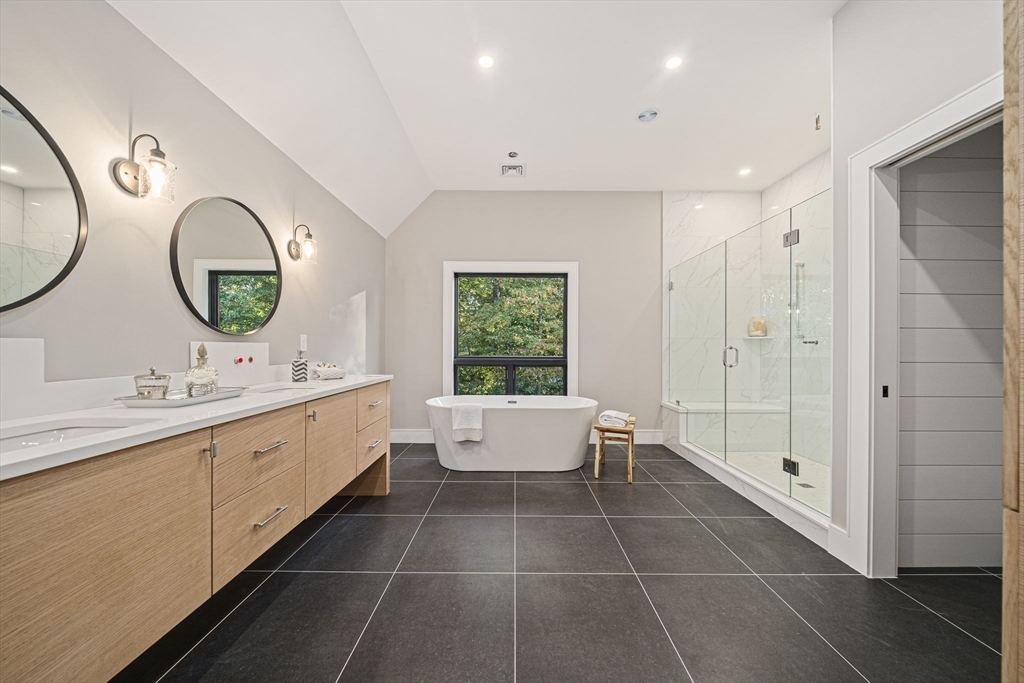 7 Ashcroft Road Sharon, MA 02067 - Photo 21 of 36 a bathroom with a double vanity sink a large mirror and a bathtub next to a window