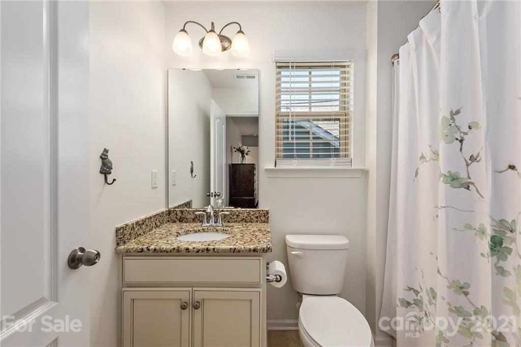 3026 Oakmere Road Waxhaw, NC 28173 - Photo 18 of 27 a bathroom with a granite countertop toilet a sink and a mirror