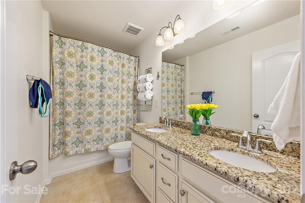 3026 Oakmere Road Waxhaw, NC 28173 - Photo 20 of 27 a bathroom with a granite countertop sink a toilet a mirror and shower curtain