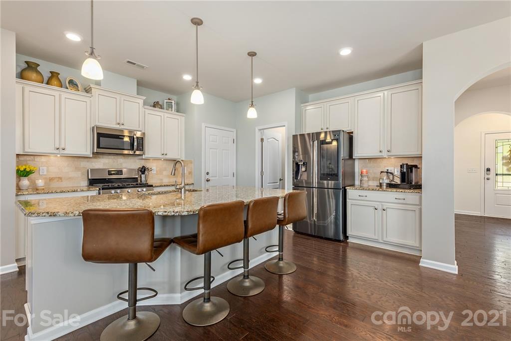 3026 Oakmere Road Waxhaw, NC 28173 - Photo 7 of 27 a kitchen with stainless steel appliances granite countertop a refrigerator a stove a sink dishwasher and a microwave with wooden floor