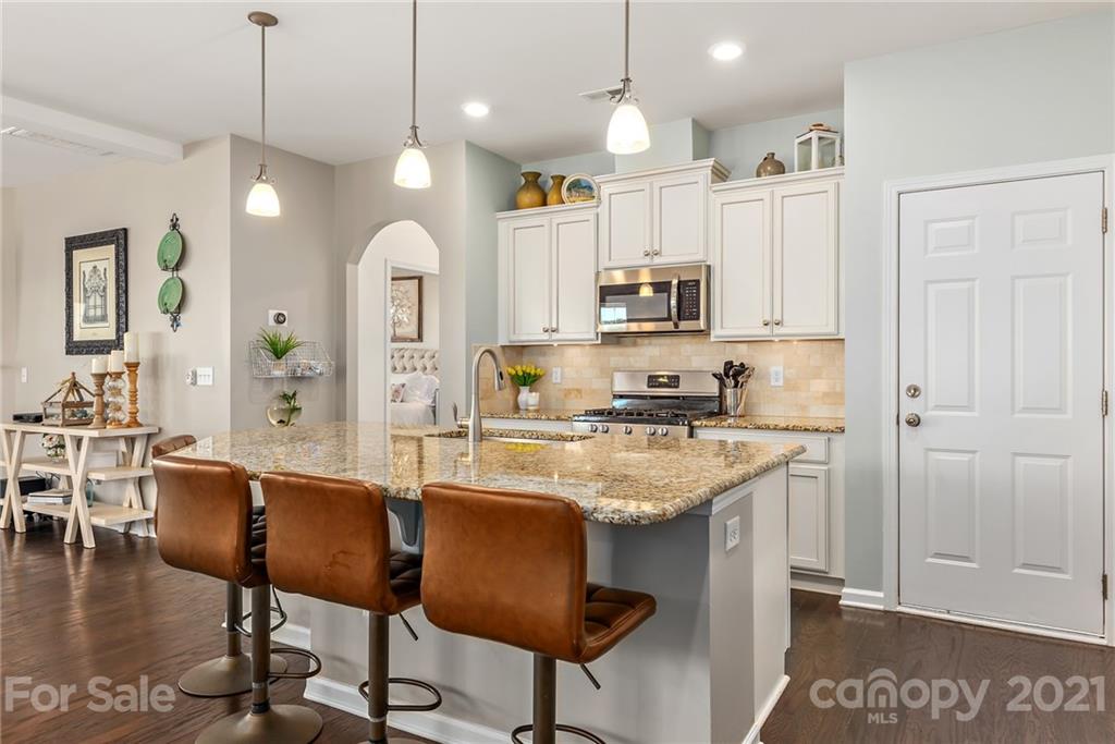 3026 Oakmere Road Waxhaw, NC 28173 - Photo 8 of 27 a kitchen with stainless steel appliances granite countertop a stove top oven a refrigerator a sink a dining table and chairs with wooden floor