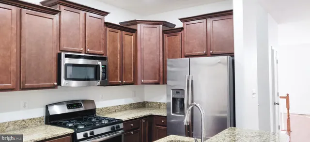 a kitchen with stainless steel appliances granite countertop a refrigerator stove and microwave