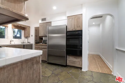 a living room with stainless steel appliances kitchen island granite countertop a refrigerator and a stove top oven