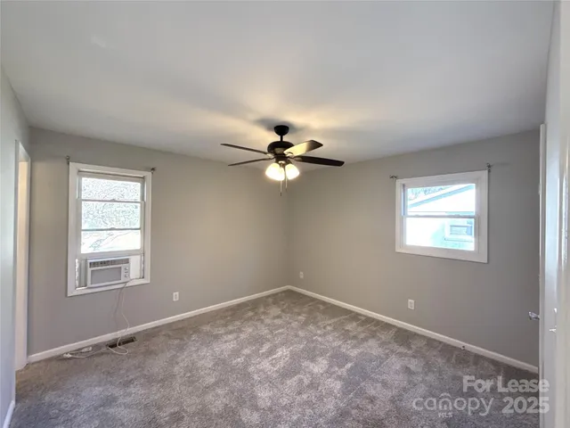 an empty room with windows and ceiling fan