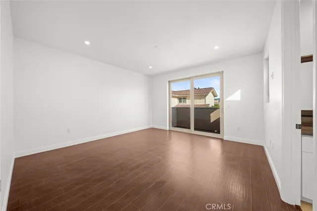 an empty room with wooden floor and kitchen