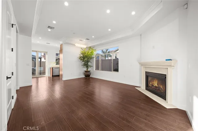 a view of an empty room with wooden floor and a fireplace