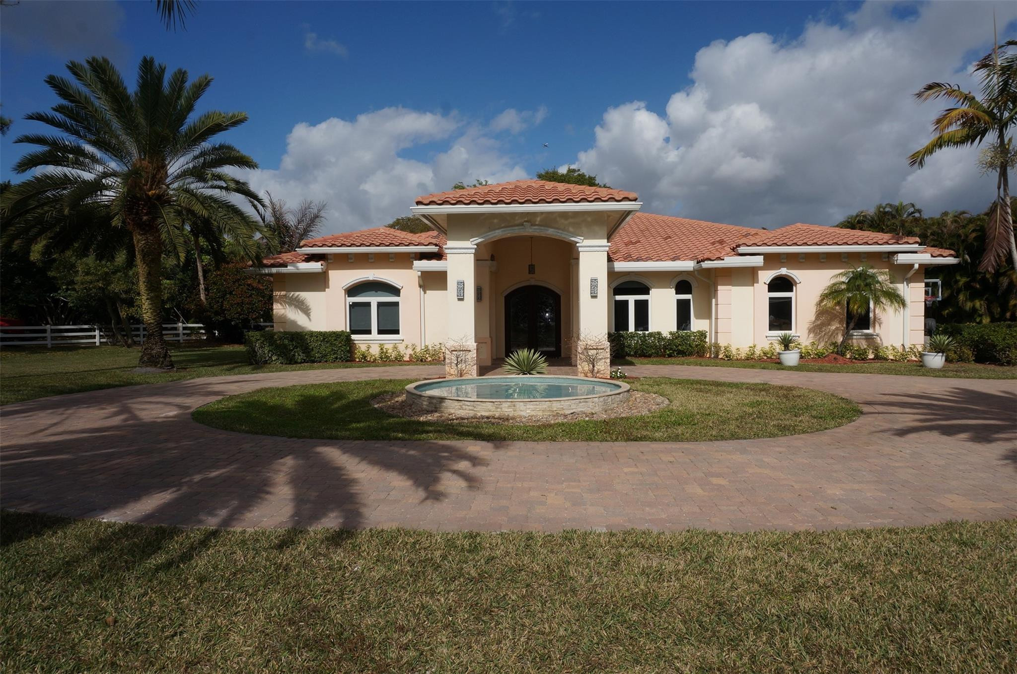 650 East Rambling Drive Wellington, FL 33414 - Photo 3 of 75 a front view of a house with a garden and trees