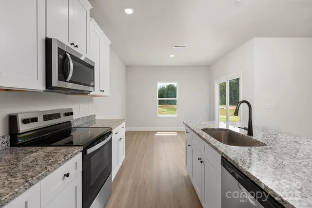 a kitchen with granite countertop a sink and steel appliances
