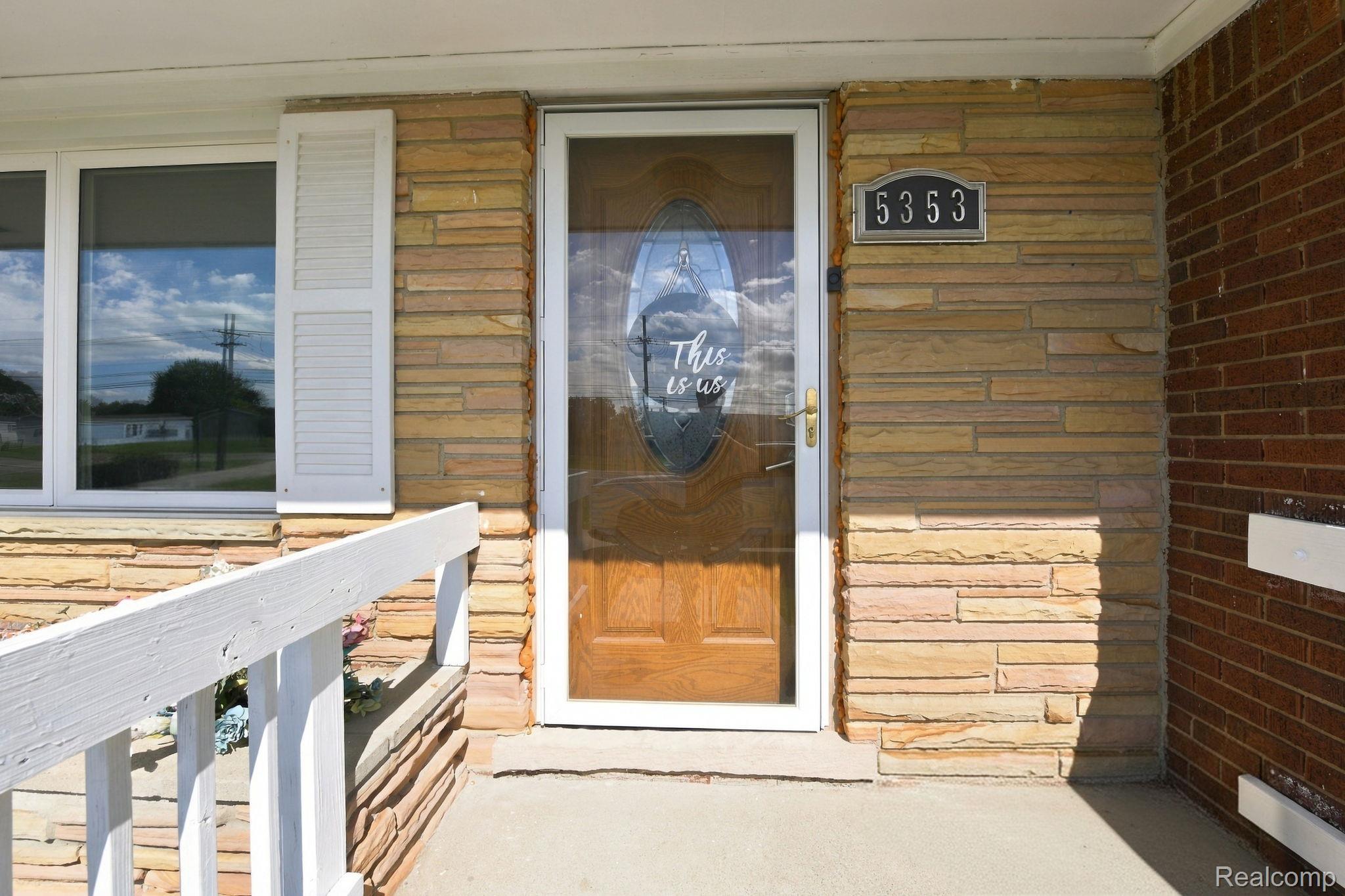 5353 18 Mile Road Sterling Heights, MI 48314 - Photo 9 of 53 Exterior featuring a stone veneer facade, white window shutters, a wood-finish entry door, and a white handrail
