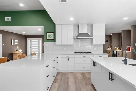a kitchen with stainless steel appliances white cabinets a sink dishwasher and a stove with wooden floor