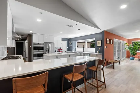 a kitchen with stainless steel appliances kitchen island granite countertop a dining table and chairs