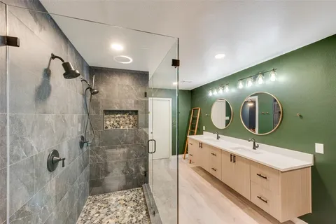 a bathroom with a double vanity sink mirror and shower