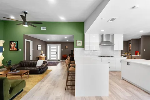 a large kitchen with stainless steel appliances kitchen island granite countertop a refrigerator a sink dishwasher a dining table and chairs with wooden floor