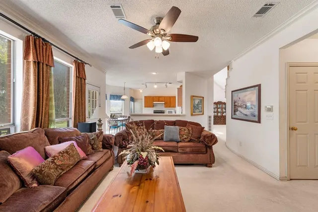 a living room with furniture ceiling fan and a large window