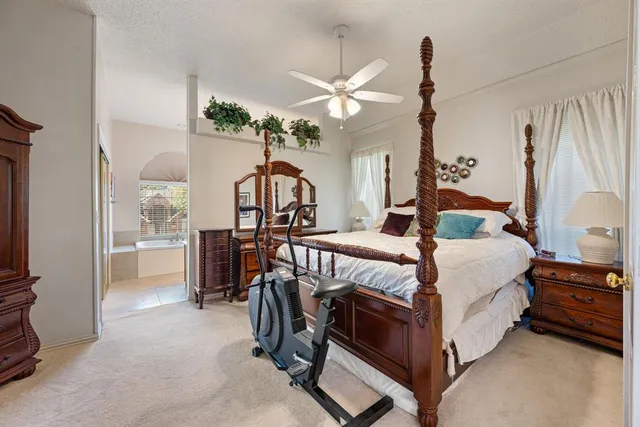 a bedroom with a bed a chandelier and dresser