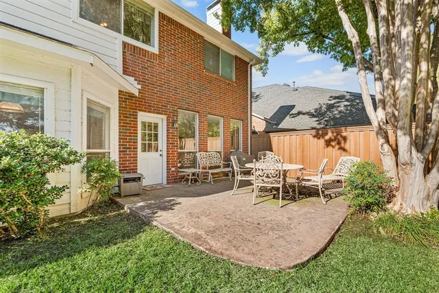 a view of a patio with table and chairs potted plants and a large tree