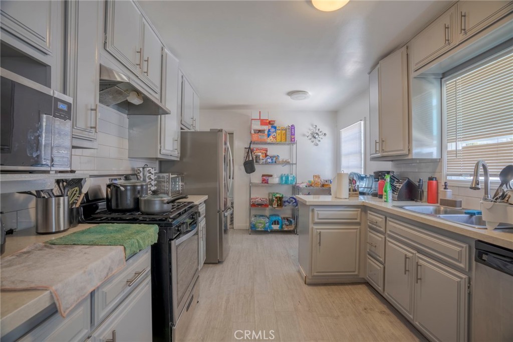 9727 Glandon Street Bellflower, CA 90706 - Photo 11 of 40 a kitchen with stainless steel appliances a refrigerator sink and cabinets
