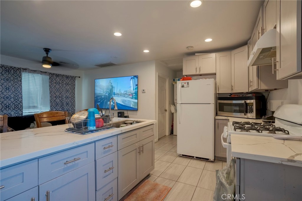 9727 Glandon Street Bellflower, CA 90706 - Photo 20 of 40 a kitchen with refrigerator a stove a sink cabinets and a counter top space