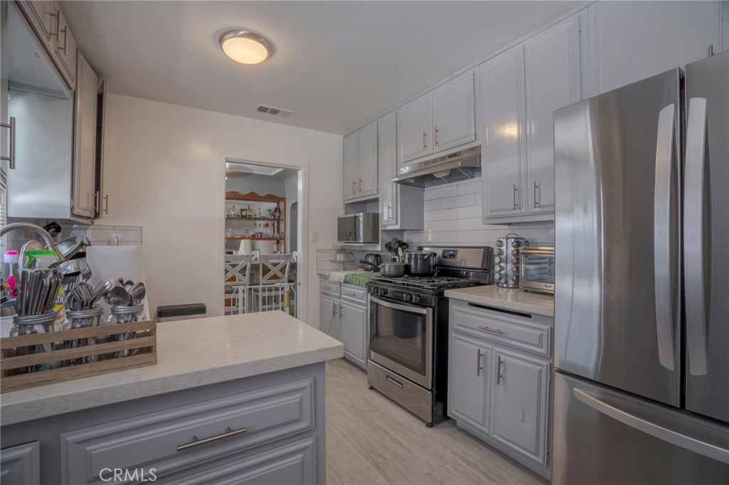 9727 Glandon Street Bellflower, CA 90706 - Photo 10 of 40 a kitchen with stainless steel appliances white cabinets and a stove top oven