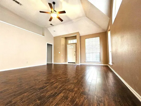 a view of an empty room with window and wooden floor