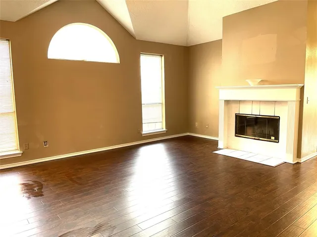 a view of an empty room with wooden floor and a fireplace